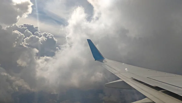 Flygplansvinge utsikt ut genom fönstret på molnigt himlen bakgrunds — Stockfoto