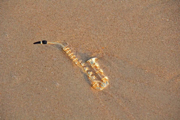 Den gyllene Altsaxofonen ligger på sanden eller på stranden. Musi — Stockfoto