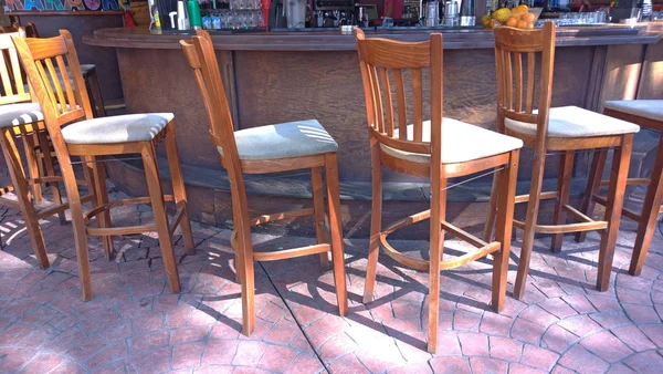 High wooden bar stools and a bar counter in the street