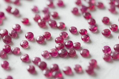 Yakut taşları beyaz bir masanın üzerinde, beyaz bir arka plan da yatıyor. Doğal st
