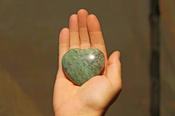 The hand holds the heart from natural stone. Heart in hand. A st — Stock Photo, Image