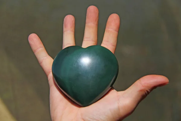 The hand holds the heart from natural stone green jade. Heart in — Stock Photo, Image