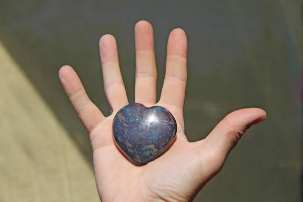 The hand holds the heart from natural stone. Heart in hand. A st — Stock Photo, Image