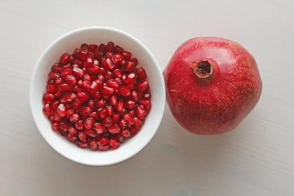 Granos de granada madura roja yacen en un tazón blanco. Grande maduro rojo — Foto de Stock