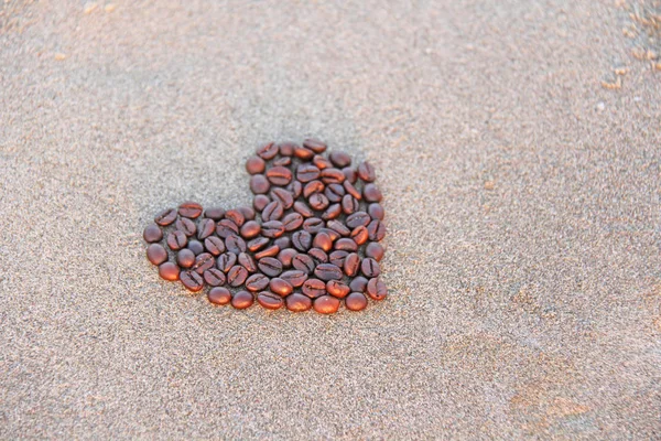 Corazón de café. Granos de café se colocan en la arena en el fo — Foto de Stock