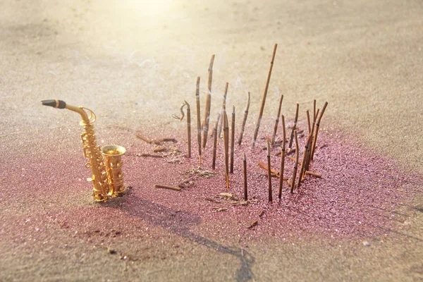El saxofón dorado alto se encuentra en la arena junto al fragante —  Fotos de Stock