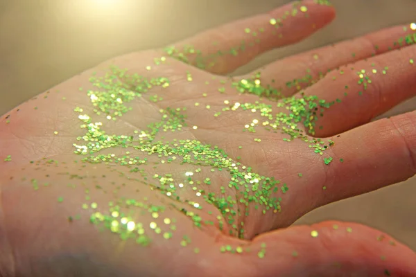 Ένα λαμπερό χέρι με γκλίτερ στον ήλιο. Λαμπρά πράσινα χέρια, μαγεία — Φωτογραφία Αρχείου