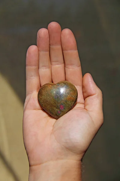 Handen håller hjärtat från den naturliga stenen i iotsit. H — Stockfoto
