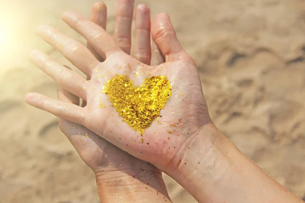 A golden shining heart lies in the hands of the girl. Heart in t