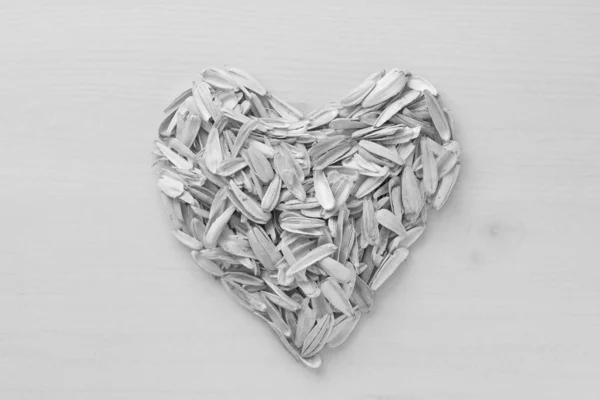 A heart made by lot of sunflower seeds. Pile of waste from seeds — Stock Photo, Image