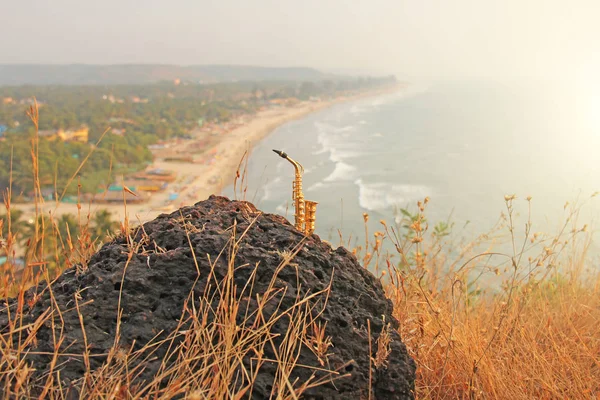 De gouden altsaxofoon staat op de achtergrond van het strand. — Stockfoto