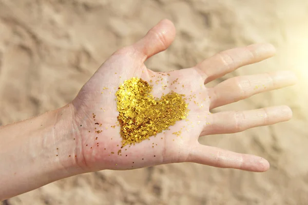 Złote świecące serce leży w rękach dziewczynki. Serce w t — Zdjęcie stockowe