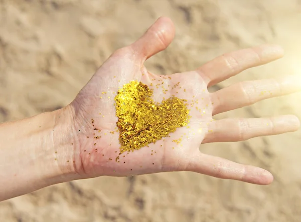 Złote świecące serce leży w rękach dziewczynki. Serce w t — Zdjęcie stockowe