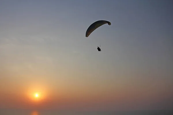 Ένα αλεξίπτωτο πλαγιάς στο φόντο της θάλασσας και του ηλιοβασιλέματος ή — Φωτογραφία Αρχείου