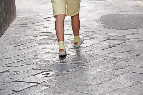 Männerfüße in hellen Schuhen und gelben Socken gehen die Straße entlang. th — Stockfoto