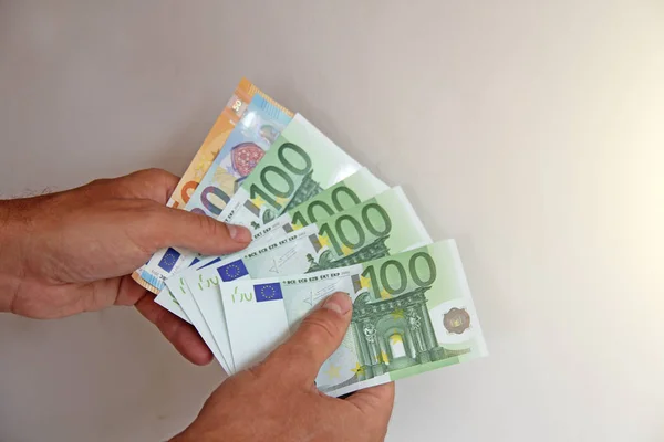 A mão do homem segura os 100 euros, considera-os e paga. Pape. — Fotografia de Stock