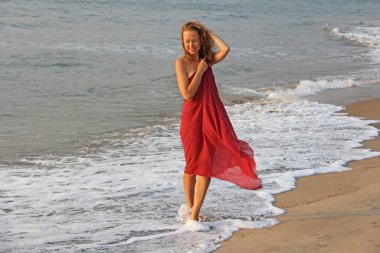 Sarı saçlı güzel bir kız, kırmızı bir elbise içinde, th boyunca yürür