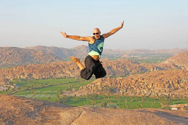 Handsome high jump man. A bald man wearing sunglasses in Hampi,