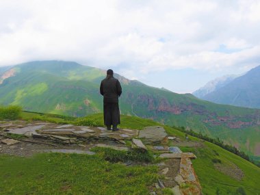Yalnız bir keşiş yeşil bir dağ üzerinde duruyor ve dist içine bakar
