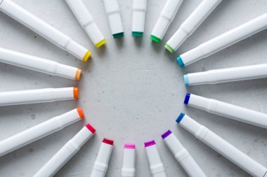 Çok renkli parlak keçeli kalemler ya da işaretler bir dairenin içinde yer alıyor, ışınlar, merkezde yuvarlak bir çerçeve oluşturuyor. Yaratıcılık, çocuklar için çizim, tasarım. Gökkuşağının her renginin birçok işareti.