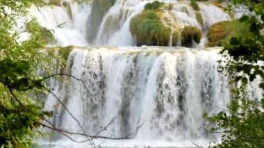 Şelaleler Krka, Ulusal Park, Hırvatistan. Krka Ulusal Parkı 'nda ağaçlar ve çimenler arasında çağlayan şelaleler arasında güzel nehirler akıyor. Su, nehir, akarsu videosu. Güzel şelale şelaleleri.