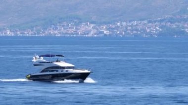 Hırvatistan, Hvar Adası, 15 Ağustos 2019. Göğüs zırhı olmayan bir adam yat kullanıyor. Mavi denizde siyah beyaz bir katamaran yatı yüksek hızda yol alıyor..