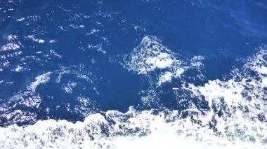 Köpüklü yüzeyi olan deniz suyu. Tekne yolculuğu, deniz köpüğü, mavi köpük, deniz arka planı dalgaları. Dalgalı derin turkuaz ve beyaz köpüklü mavi Akdeniz. Tekne uyanışından su püskürtme. Yavaş çekim videosu.