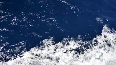 Köpüklü yüzeyi olan deniz suyu. Tekne yolculuğu, deniz köpüğü, mavi köpük, deniz arka planı dalgaları. Dalgalı derin turkuaz ve beyaz köpüklü mavi Akdeniz. Tekne uyanışından su püskürtme. Yavaş çekim videosu.