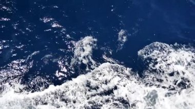Köpüklü yüzeyi olan deniz suyu. Tekne yolculuğu, deniz köpüğü, mavi köpük, deniz arka planı dalgaları. Dalgalı derin turkuaz ve beyaz köpüklü mavi Akdeniz. Tekne uyanışından su püskürtme. Yavaş çekim videosu.