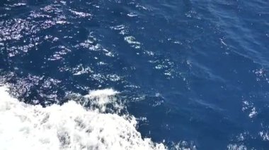 Köpüklü yüzeyi olan deniz suyu. Tekne yolculuğu, deniz köpüğü, mavi köpük, deniz arka planı dalgaları. Dalgalı derin turkuaz ve beyaz köpüklü mavi Akdeniz. Tekne uyanışından su püskürtme. Yavaş çekim videosu.