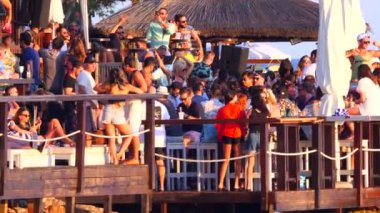 Hırvatistan, Hvar Adası, 15 Ağustos 2019. Birçok genç insan deniz kıyısında müzik eşliğinde dans edip kokteyl içer. Gün batımında mayo giymiş bir yaz partisi. Eğlence ve gençlik eğlencesi.