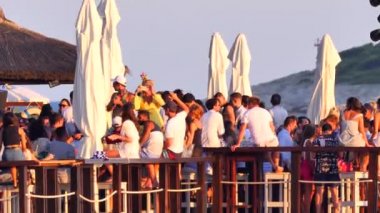 Hırvatistan, Hvar Adası, 15 Ağustos 2019. Birçok genç insan deniz kıyısında müzik eşliğinde dans edip kokteyl içer. Gün batımında mayo giymiş bir yaz partisi. Eğlence ve gençlik eğlencesi.