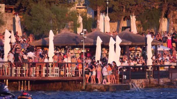 クロアチア Hvar島 2019年8月15日 多くの若者が海岸でカクテルを踊りながら音楽に合わせています 日没の水着で夏のパーティー 楽しさと若者のレクリエーション スローモーションビデオ — ストック動画