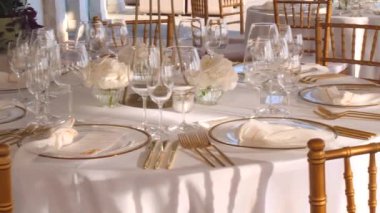 Hırvatistan 'ın Hvar adasındaki deniz kıyısında, beyaz-altın renkli düğün masasının güzel dekorasyonu. Denizde düğün. Altın çatal bıçak takımı. Güzel bir düğün. Zarif altın ve beyaz masa..