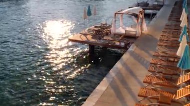 Boş tahta şezlong, güneşlenmek için güzel çadırlar, deniz kıyısında dinlenme çadırları, Hırvatistan 'da körfez, Hvar adası. Akşam deniz batımı, dinlenme, tatil. Sandalyeler, dinlenmeye hazır insanlar..