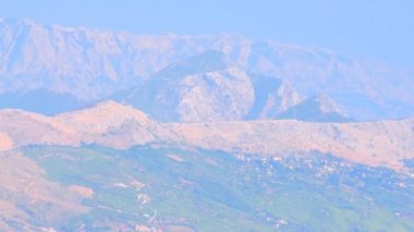 Split kenti yakınlarındaki Hırvat dağlarının manzarası. Mavi dağlar ve fayanslı terakotta çatılı evler, yazın sıcak hava görünür, havada bir serap.