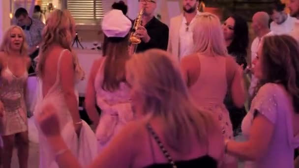 克罗地亚 Hvar岛 2019年8月16日 男声萨克斯演奏家在婚宴 公司活动 宴会上演奏金黄色的阿尔托萨克斯风 穿着晚礼服的漂亮姑娘 男人们玩的开心 和萨克斯风一起跳舞 — 图库视频影像