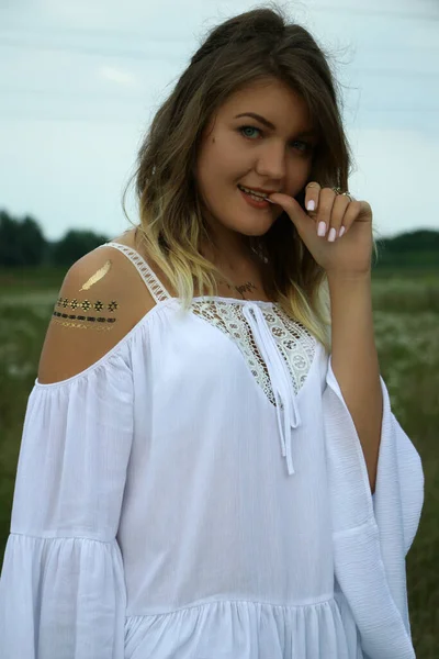 Retrato de una mujer hermosa coqueta feliz en blusa blanca en el campo. Tatuaje temporal. Dibujos en el cuerpo. hippie . —  Fotos de Stock