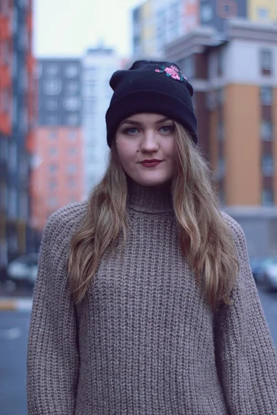 Miejski portret flirtującej pięknej kobiety w brązowym swetrze, dżinsach i czarnym kapeluszu. na parkingu — Zdjęcie stockowe