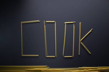 Word COOK gri arka planda spagetti ile yazılmış, üst görünüm, kopyalama alanı. Yemek malzemeleri, karantinada gıda bağışı, koronavirüs... 