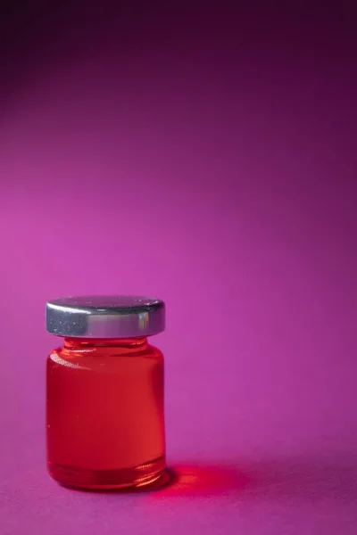 Kis üveg piros folyadék rózsaszín háttér. Elszigetelve. Társasjátékok. Gyógymód - gyógyszer, vakcina. Coronavirus vagy covid-19 - pandémia — Stock Fotó