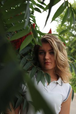 Tropikal ormanda elinde ağaç dalı tutan beyaz spor elbiseli güzel bir kadının portresi. Lüks tatil köyü