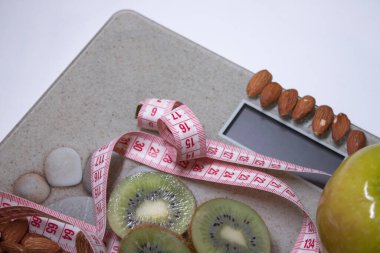 Kırmızı mezura, elma, kivi ve bej banyodaki bademler. Diyet ve sağlıklı yaşam, kilo verme, spor konsepti. Üst Manzara. Uzayı kopyala İzole edilmiş. Beyaz arkaplan