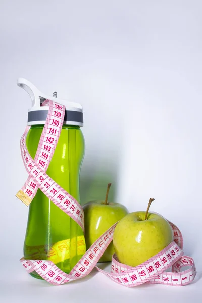 Czerwona taśma pomiarowa nad zieloną butelką sportową i zielonym jabłkiem. Dieta i zdrowe życie, utrata wagi, koncepcja sportu. Widok góry. Odbiór. Odizolowany. Białe tło — Zdjęcie stockowe