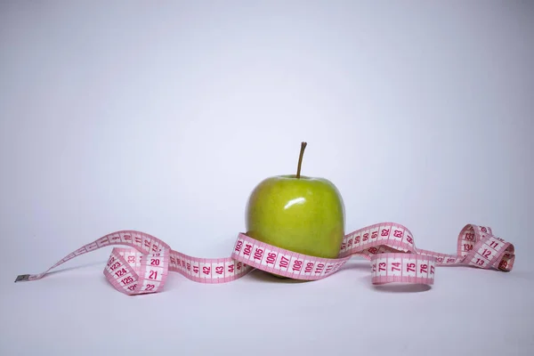 Czerwona taśma pomiarowa na zielonym jabłku. Dieta i zdrowe życie, koncepcja utraty wagi. Widok góry. Odbiór. Odizolowany. Białe tło — Zdjęcie stockowe