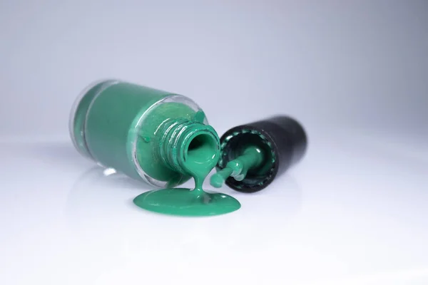 Egy palack kiömlött zöld körömlakk fehér háttér. körömlakk. Köröm manikűr koncepció. Elszigetelt, másolt tér — Stock Fotó