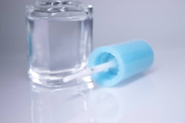 Beyaz arka planda temiz tırnak cilası dökülmüş bir şişe. Tırnak törpüsü. Tırnak manikürü konsepti. İzole edilmiş, kopyalama alanı