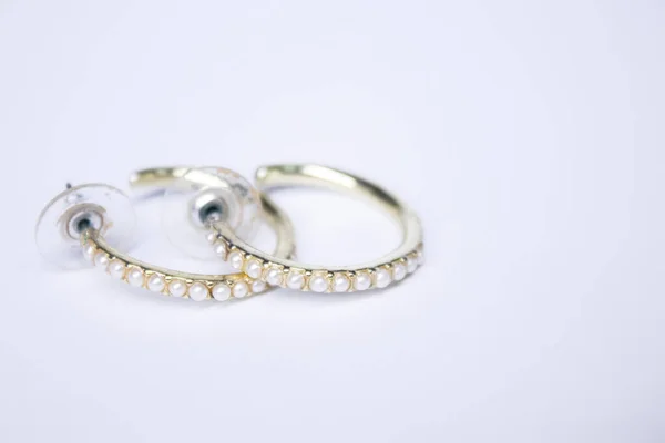 Ronde gouden oorbellen met witte stenen. sieraden en accessoires concept. Geïsoleerd, kopieerruimte. Macro neergeschoten. — Stockfoto