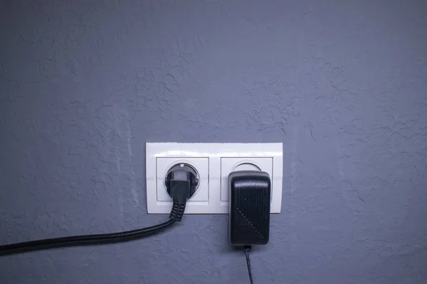 Sockets for electrical appliances on a light gray wall. a multifunction outlet