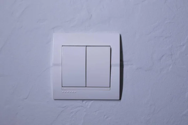 Пластиковый механический белый выключатель, установленный на светло-серой стене — стоковое фото